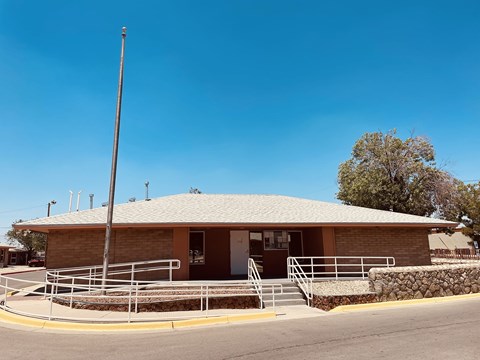 A small building with a brown roof and a stone wall in front.