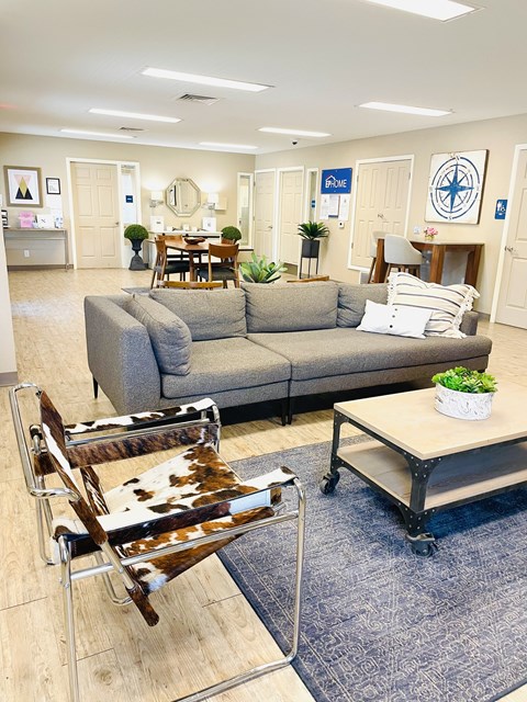 A living room with a grey couch and a cowhide chair.