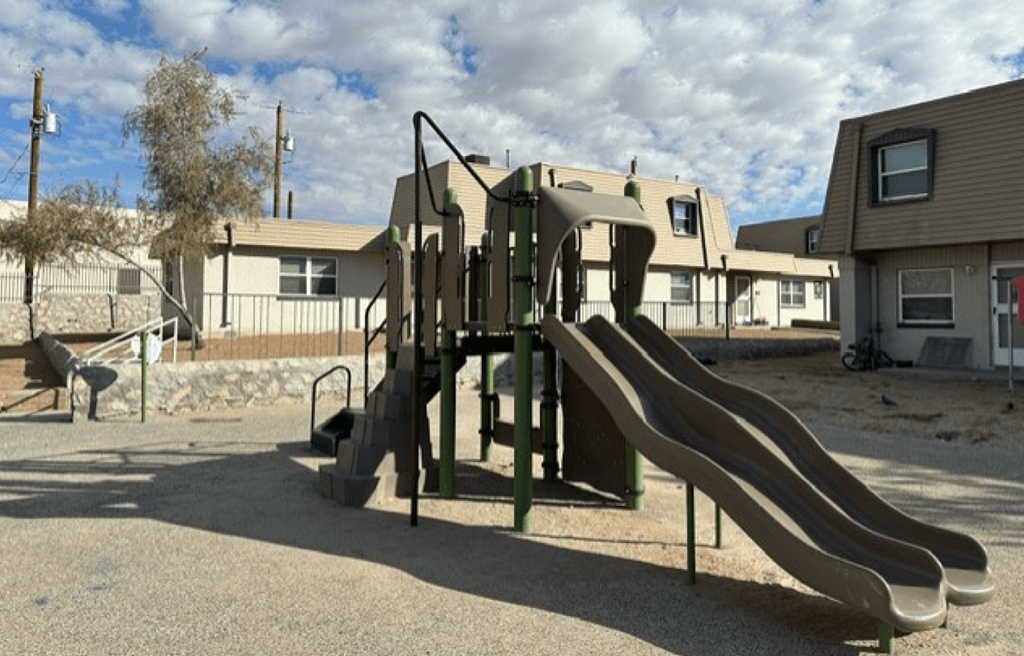 A playground with a slide and a green climbing frame.