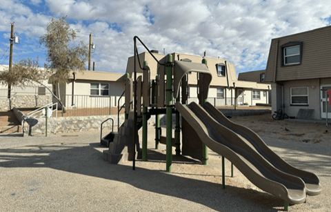 A playground with a slide and a green climbing frame.