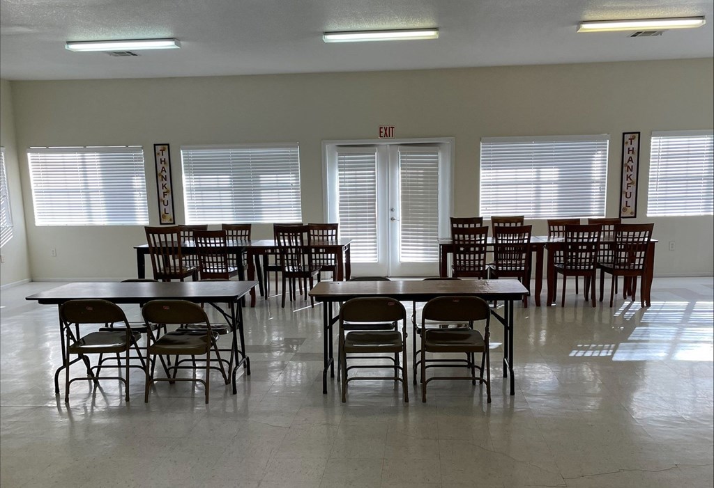 A room with tables and chairs and an exit sign.
