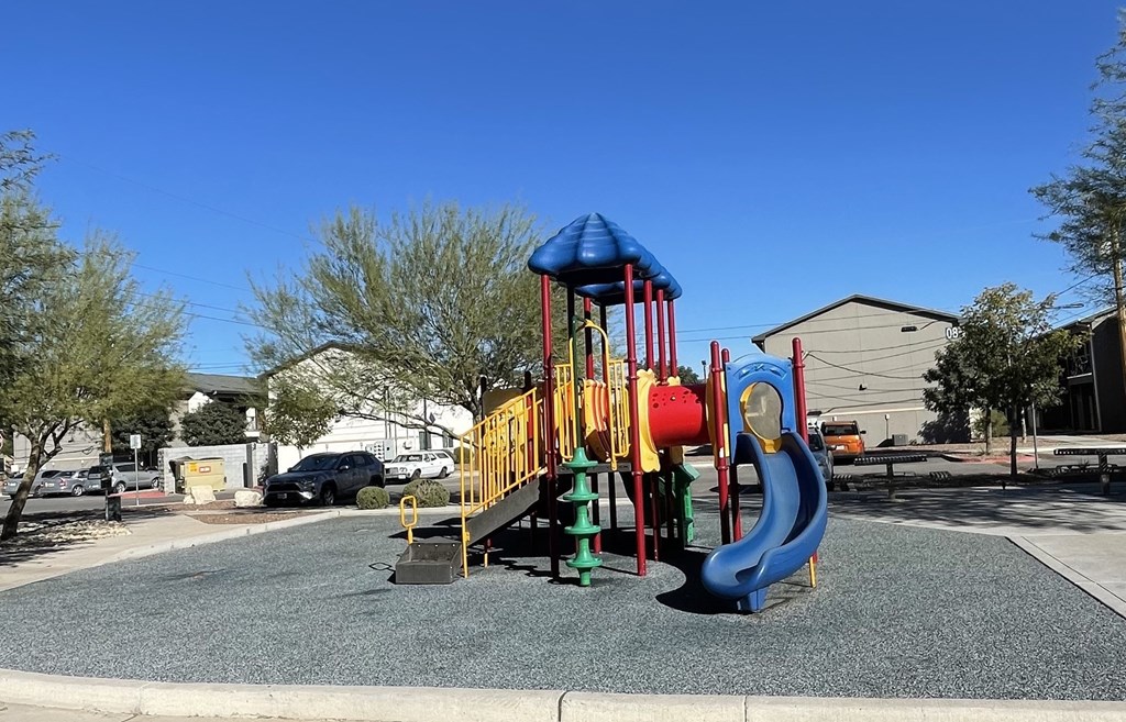 A playground with a blue slide and a red and yellow structure.