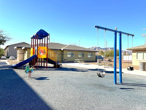 A playground with a blue swing set and a yellow slide.