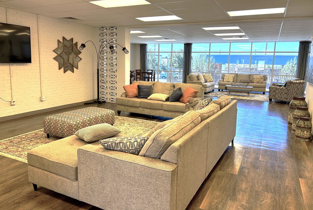 A living room with a large sectional sofa and a flat screen TV mounted on the wall.