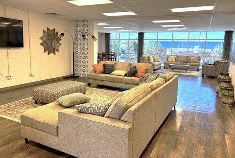 A living room with a large sectional sofa and a flat screen TV mounted on the wall.