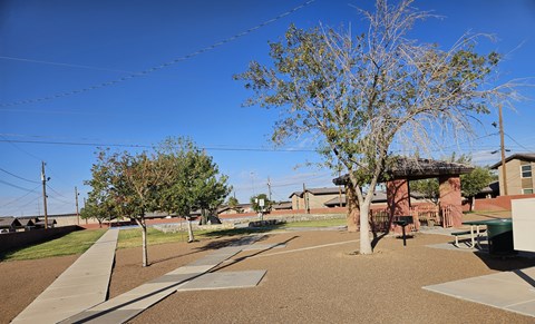 A playground with a swing set and a tree.