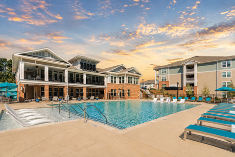 A large swimming pool in front of a building with a sunset in the background.