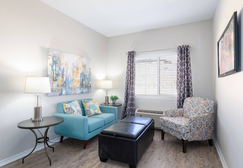 A living room with a blue couch, a patterned chair, and a small table.