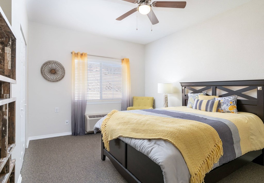 A bedroom with a bed, pillows, and a ceiling fan.