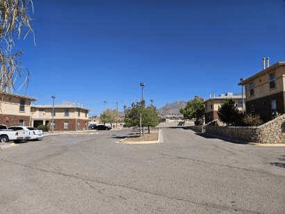 A parking lot with a few cars and buildings in the background.