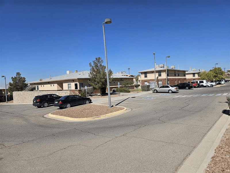 A parking lot with cars and a building in the background.