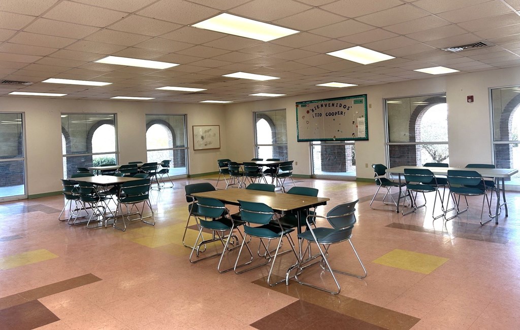 A classroom with tables and chairs and a sign that says "The First Floor is the Cafeteria.".