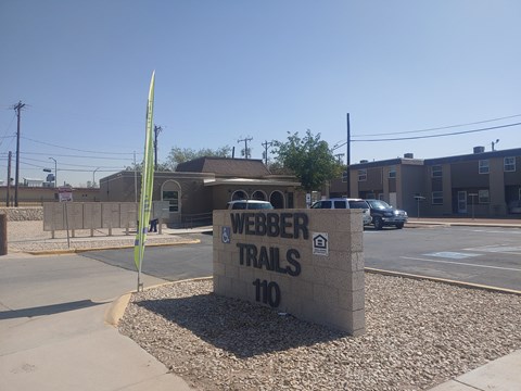 A sign for Weber Trails 110 is in front of a building.