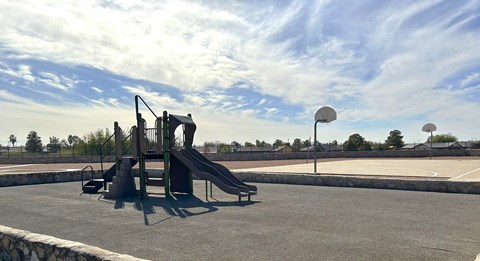 A playground with a slide and a basketball court.