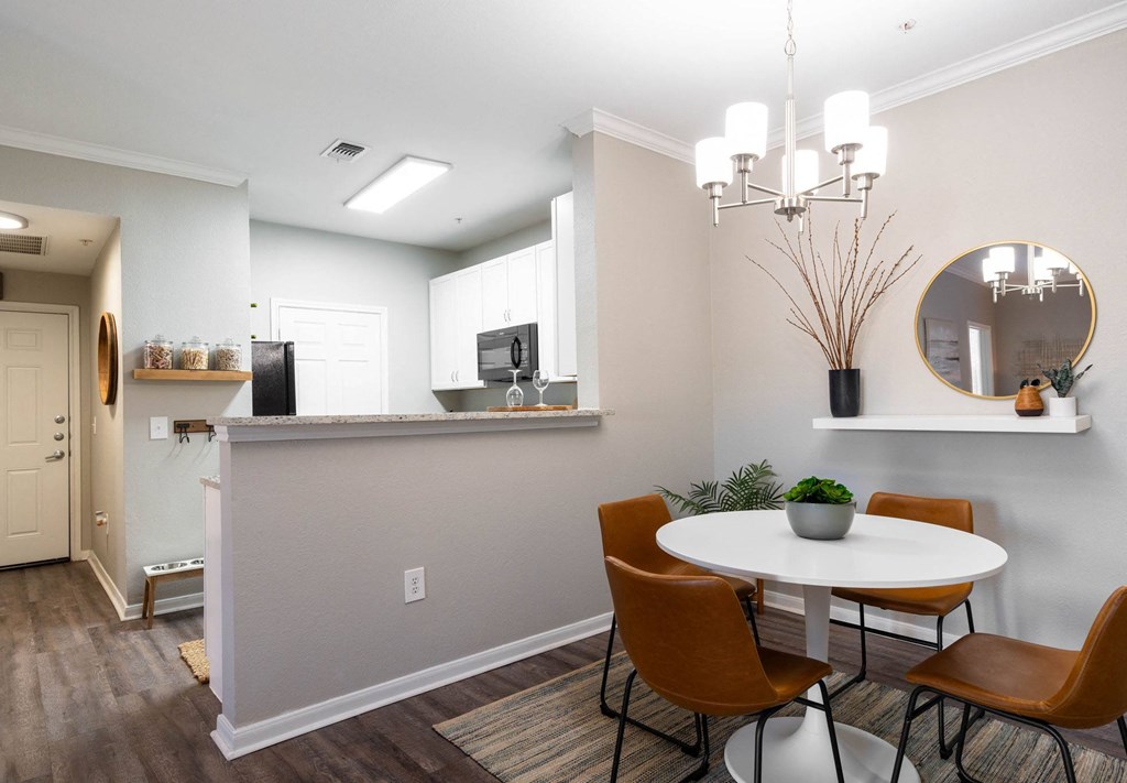 A dining room with a white table and brown chairs.