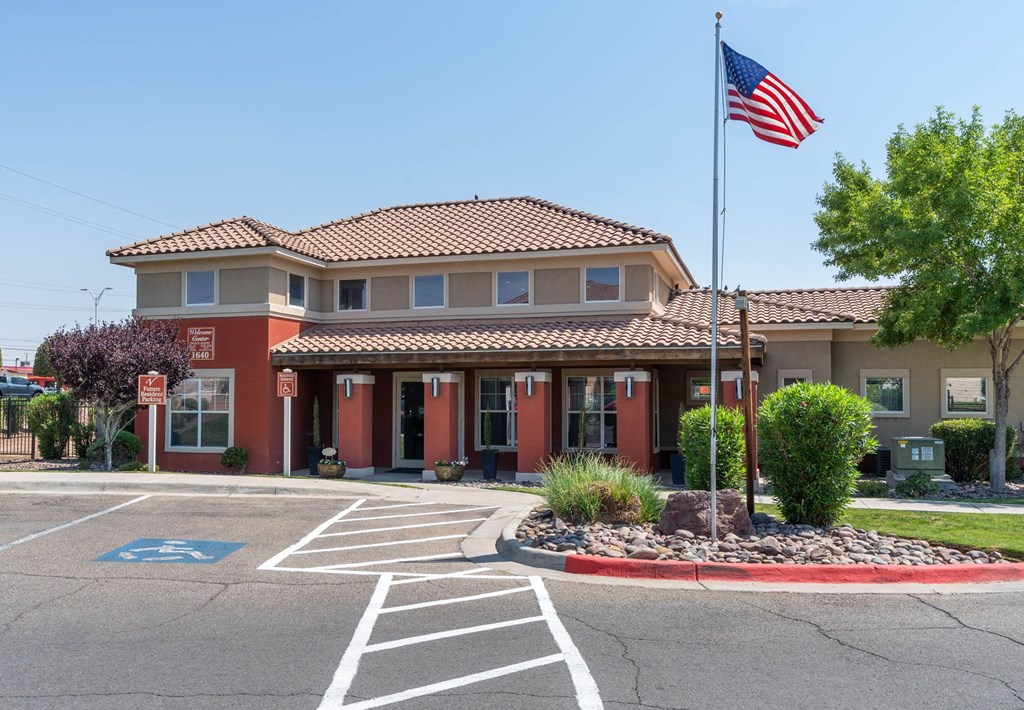 A building with a flag on top and a parking lot in front.