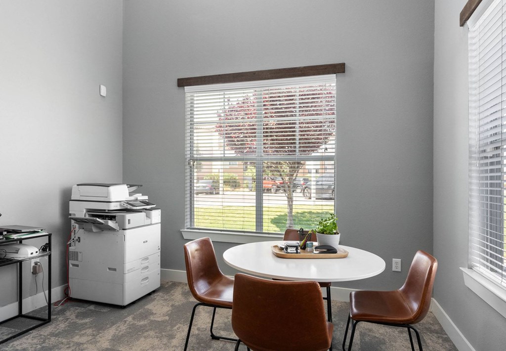 A room with a table and chairs and a window with blinds.
