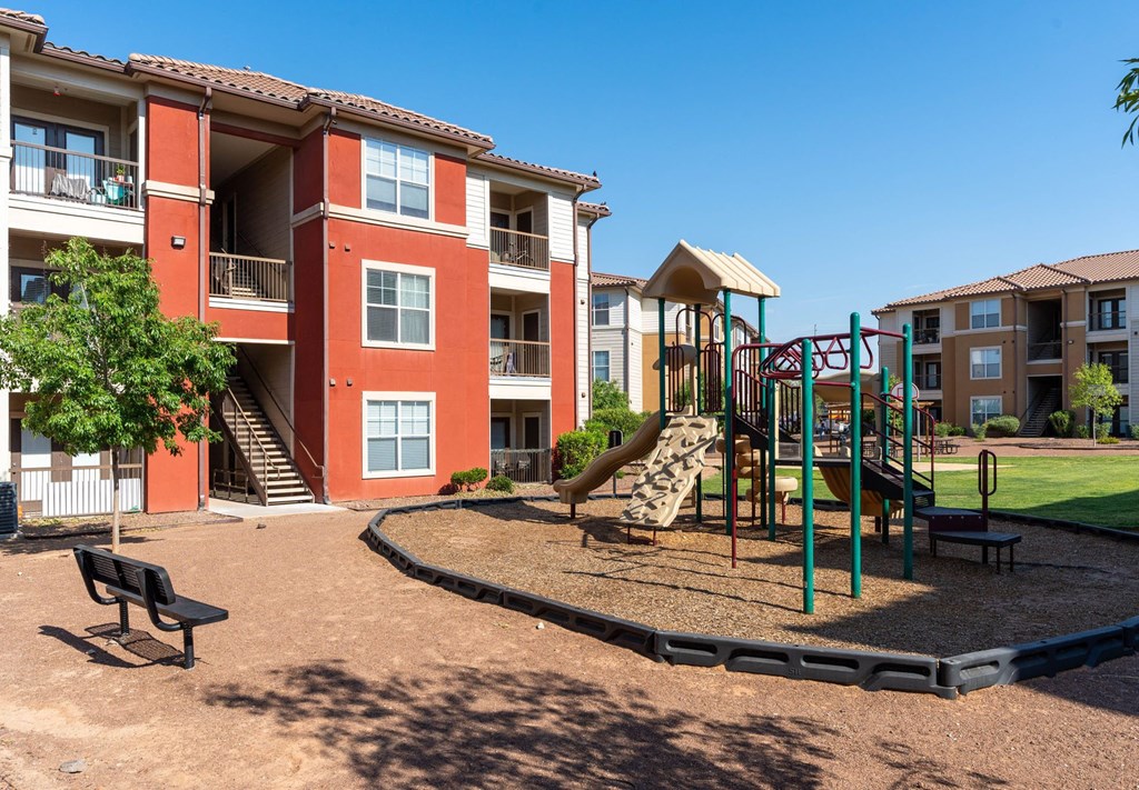 A playground area in front of a red apartment building.