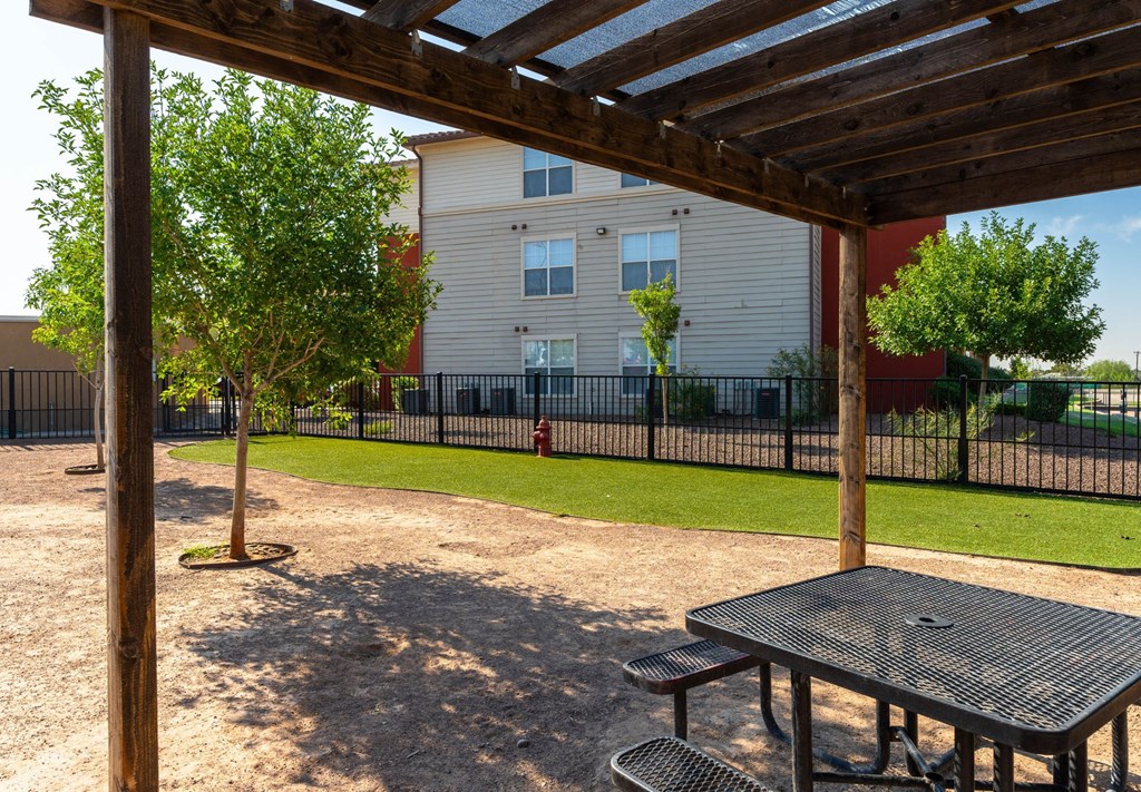 A wooden pergola over a picnic table in a park.