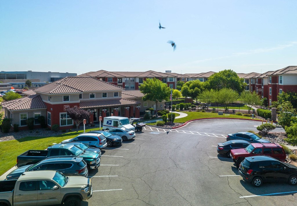 A parking lot with cars and a bird flying in the sky.
