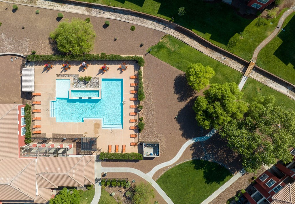 An aerial view of a pool surrounded by trees and a grassy area.