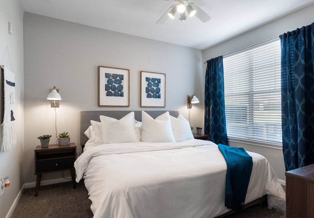 A bedroom with a large bed and two lamps.