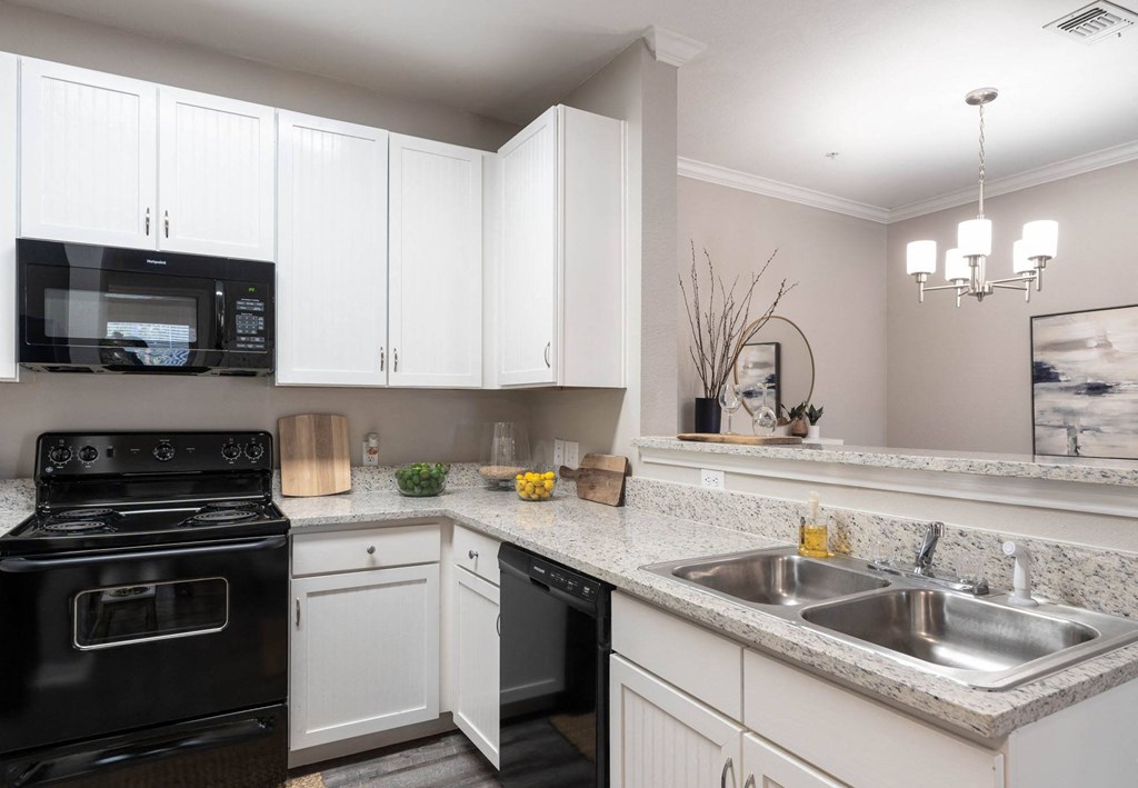 A kitchen with black appliances and white cabinets.