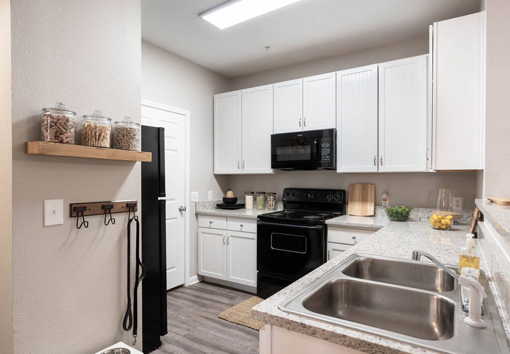 A kitchen with black appliances and white cabinets.