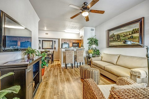 A living room with a couch, chairs, and a ceiling fan.