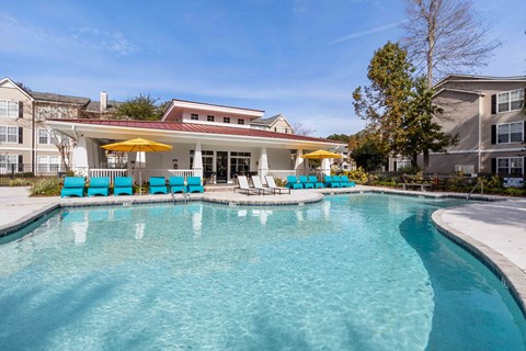 A swimming pool with blue chairs and a yellow umbrella.