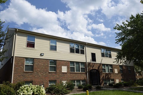 the exterior of a brick apartment building with a cloudy blue sky