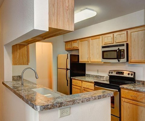 A kitchen with wooden cabinets and a granite countertop.