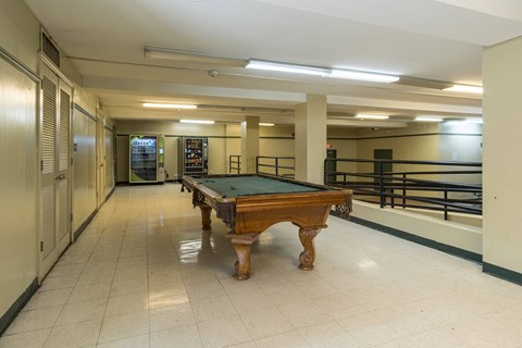 A pool table in a room with a white floor and walls.