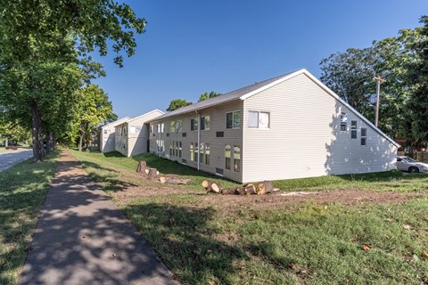 A white mobile home sits on a grassy lot with a sidewalk in front.