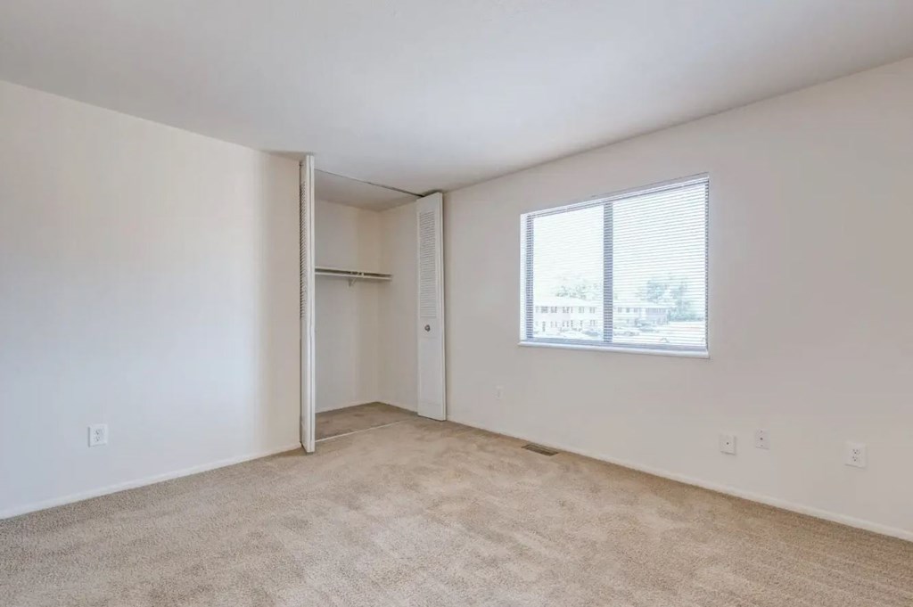 a bedroom with a large window and white walls
