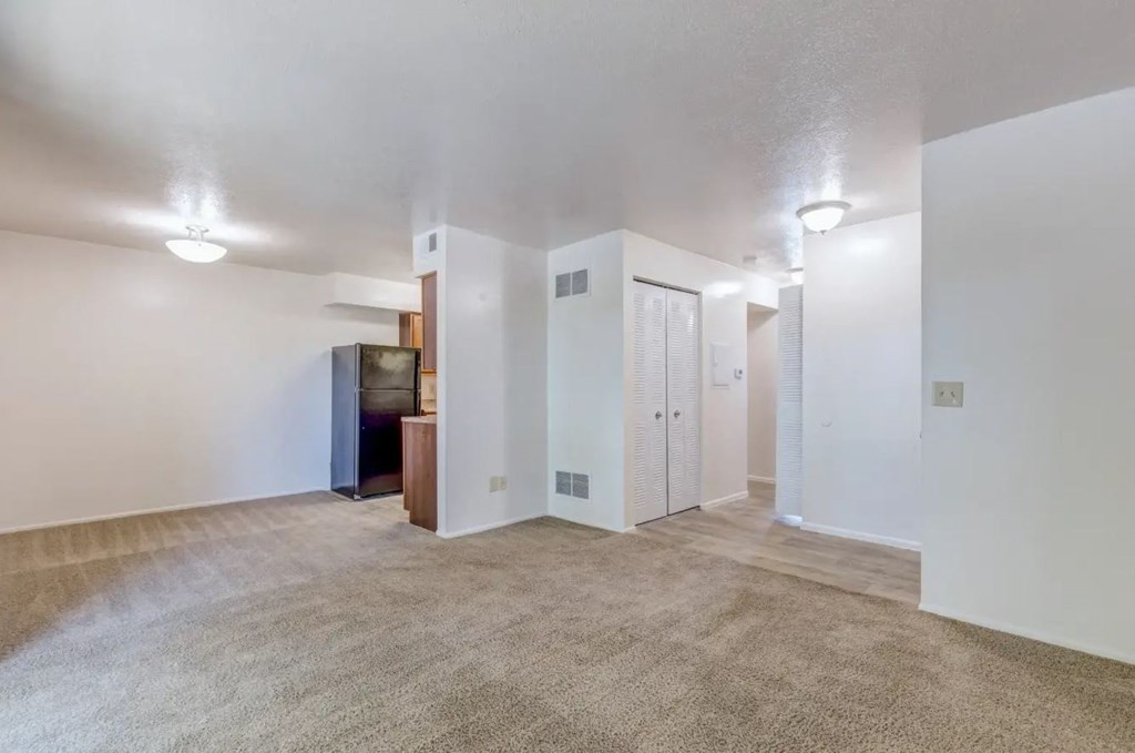 a spacious living room with white walls and beige carpet