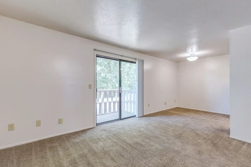 an empty living room with a sliding glass door and a balcony
