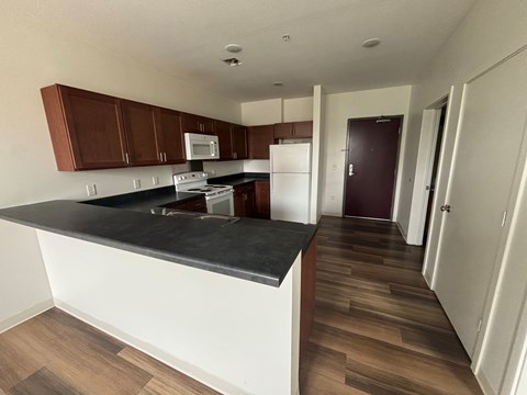 A kitchen with brown cabinets and a black countertop.