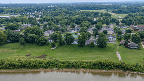 Aerial view of apartment community near river with green spaces