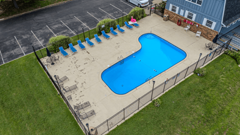 Fenced apartment pool with lounge chairs and patio seating