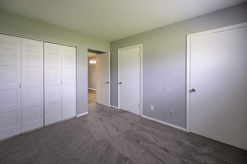 a bedroom with three closets and a carpeted floor