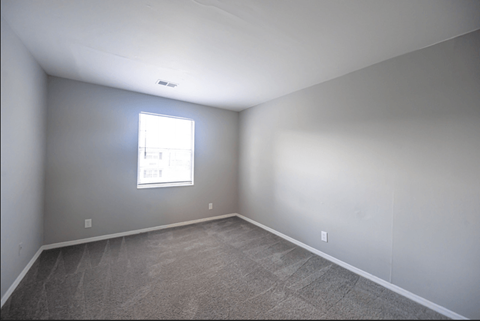 an empty room with a window and carpeting