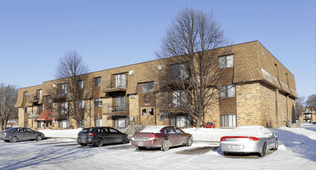 a brick apartment building with cars parked in the snow