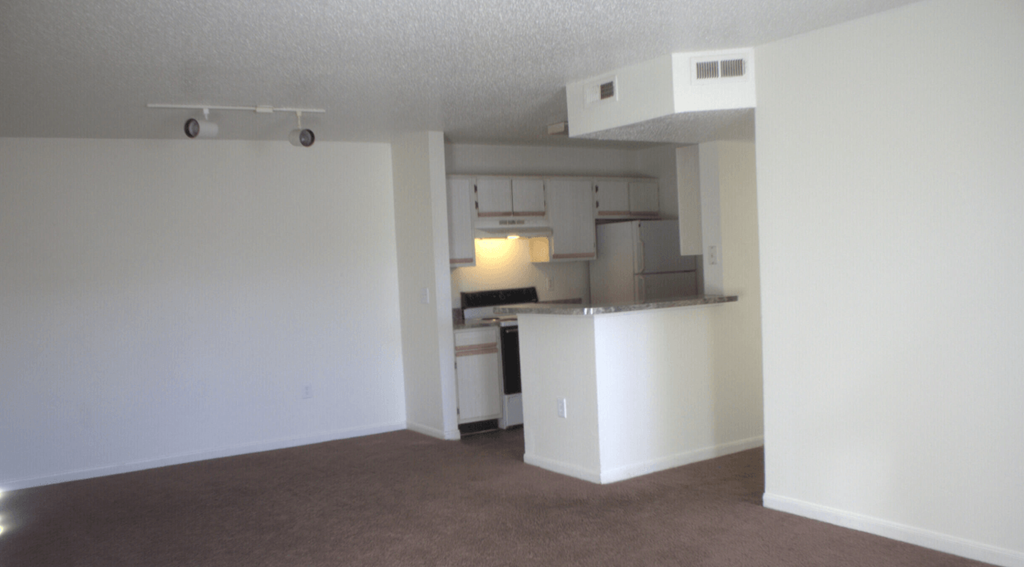 an empty living room with a kitchen in it