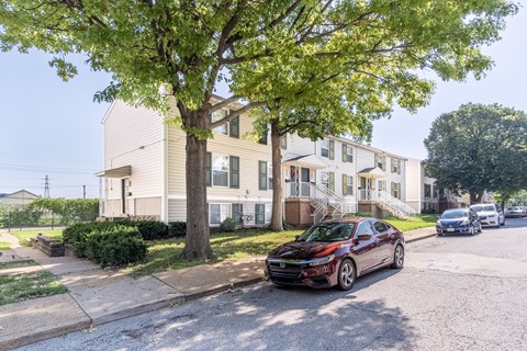 A red car is parked on a street in front of a building.