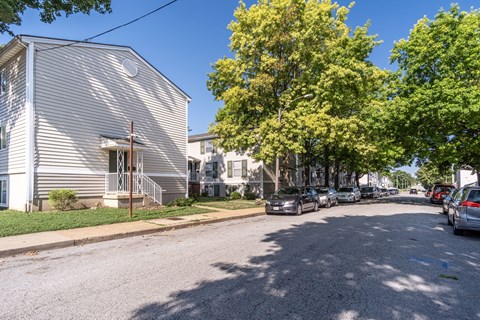 A residential street with houses and parked cars.