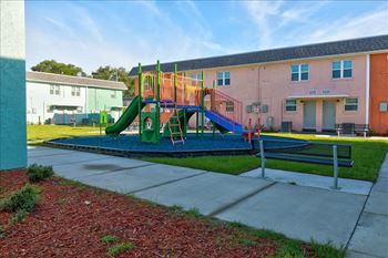 A playground with a green slide and a blue railing.