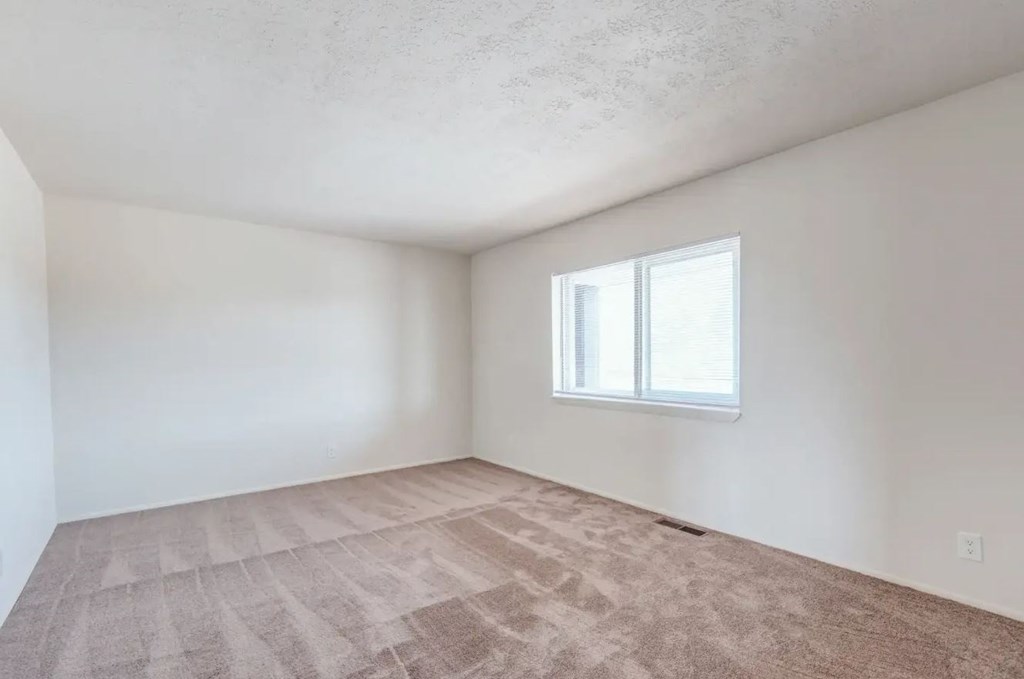 an empty room with a window and a carpeted floor