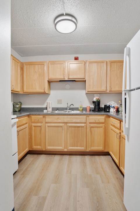 A kitchen with wooden cabinets and a white refrigerator.