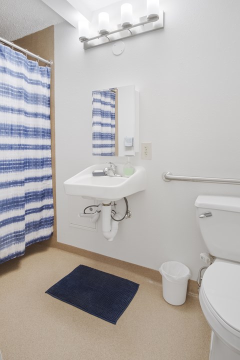 A white sink with a blue and white striped shower curtain.